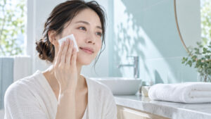 女性がコットンを頬にやさしく滑らせてスキンケアをしている様子