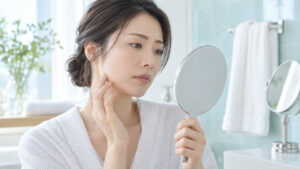女性が鏡で頬の肌状態を落ち着いて確認している様子
